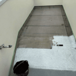 ベランダ床のFRP防水でガラス繊維マットを貼る工程の写真